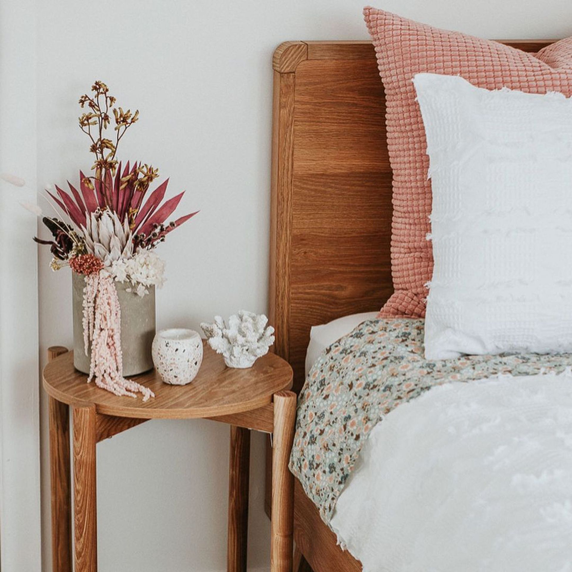 Buket bunga Antipodean tonal di meja samping tempat tidur pedesaan