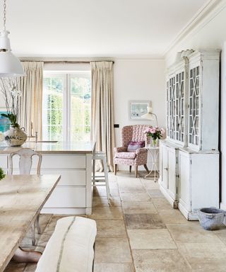 An open-plan country style cream kitchen with a dining table, an island and a french dresser