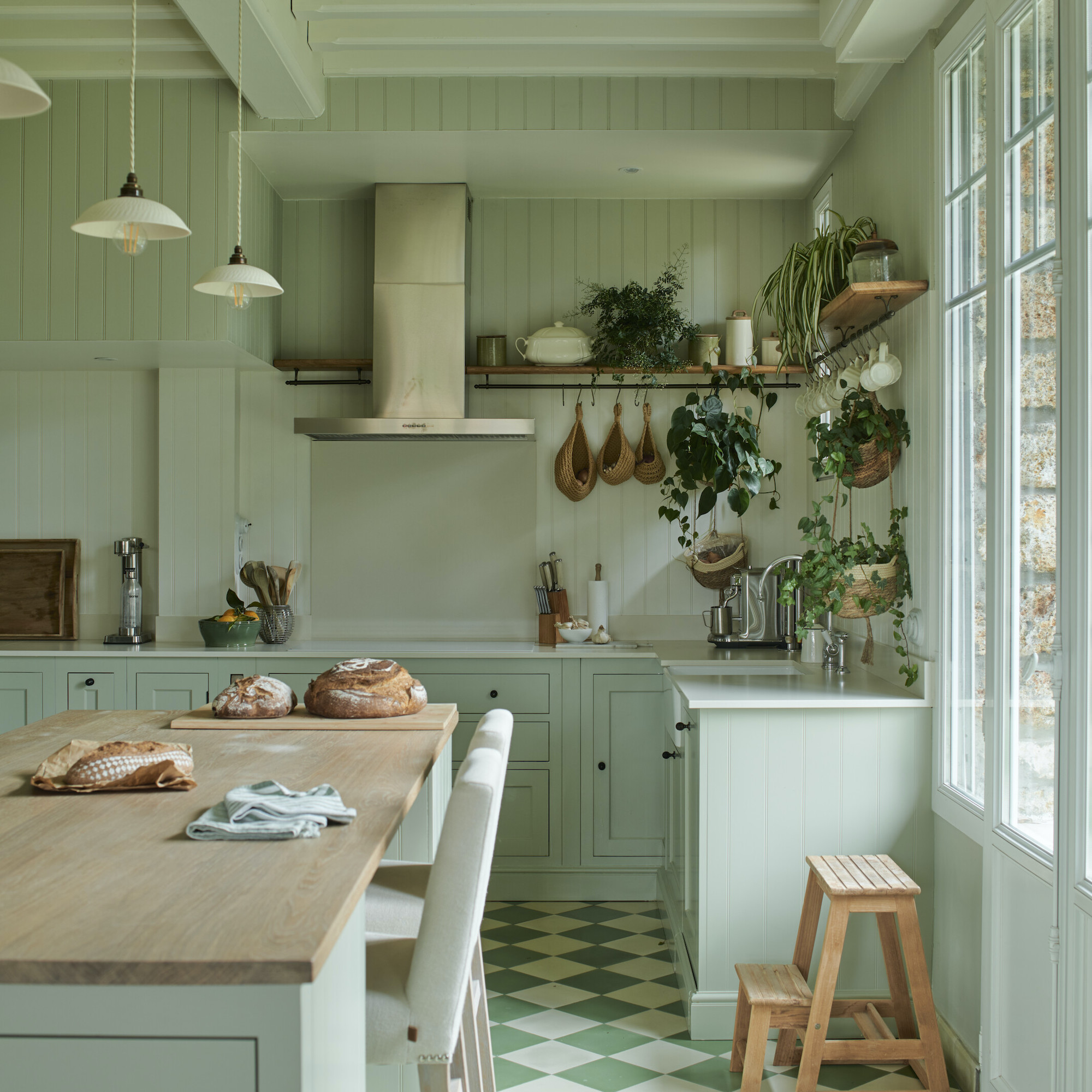 pale green kitchen with checkered floor tiles and steel extractor