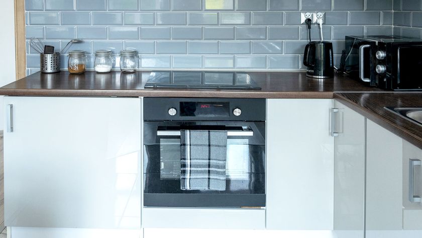 Contemporary white gloss kitchen cabinets and doors with a dark worktop and grey metro tiles