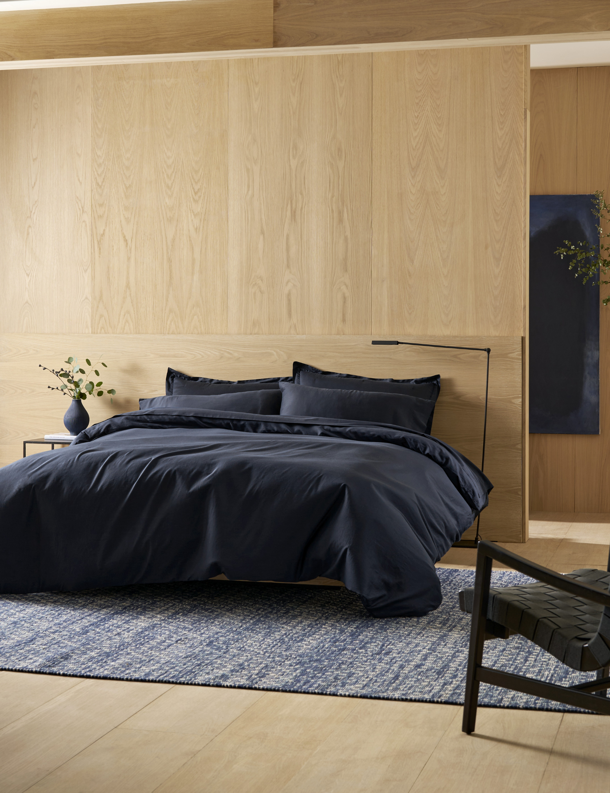 Cozy Earth Soft-Wash Bedding in Eclipse styled atop a modern low-slung bed inside of a neutral wood-paneled bedroom area