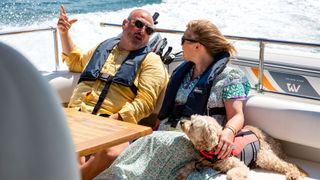 Wynne and Joanna chatting and looking at one another on a moving boat as it speeds through the sea