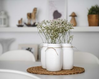 A trio of painted Mason jars with gypsophilia flowers and brown twine