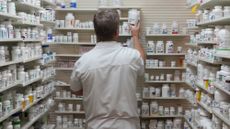 A pharmacist pulls a drug from a shelf inside a pharmacy