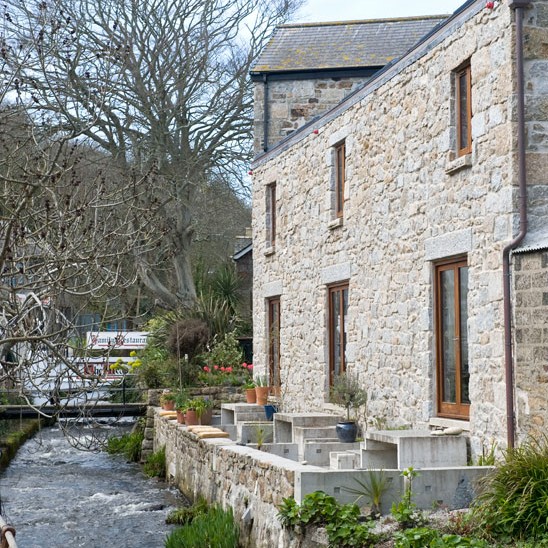 exterior of house with white stone wall and plants