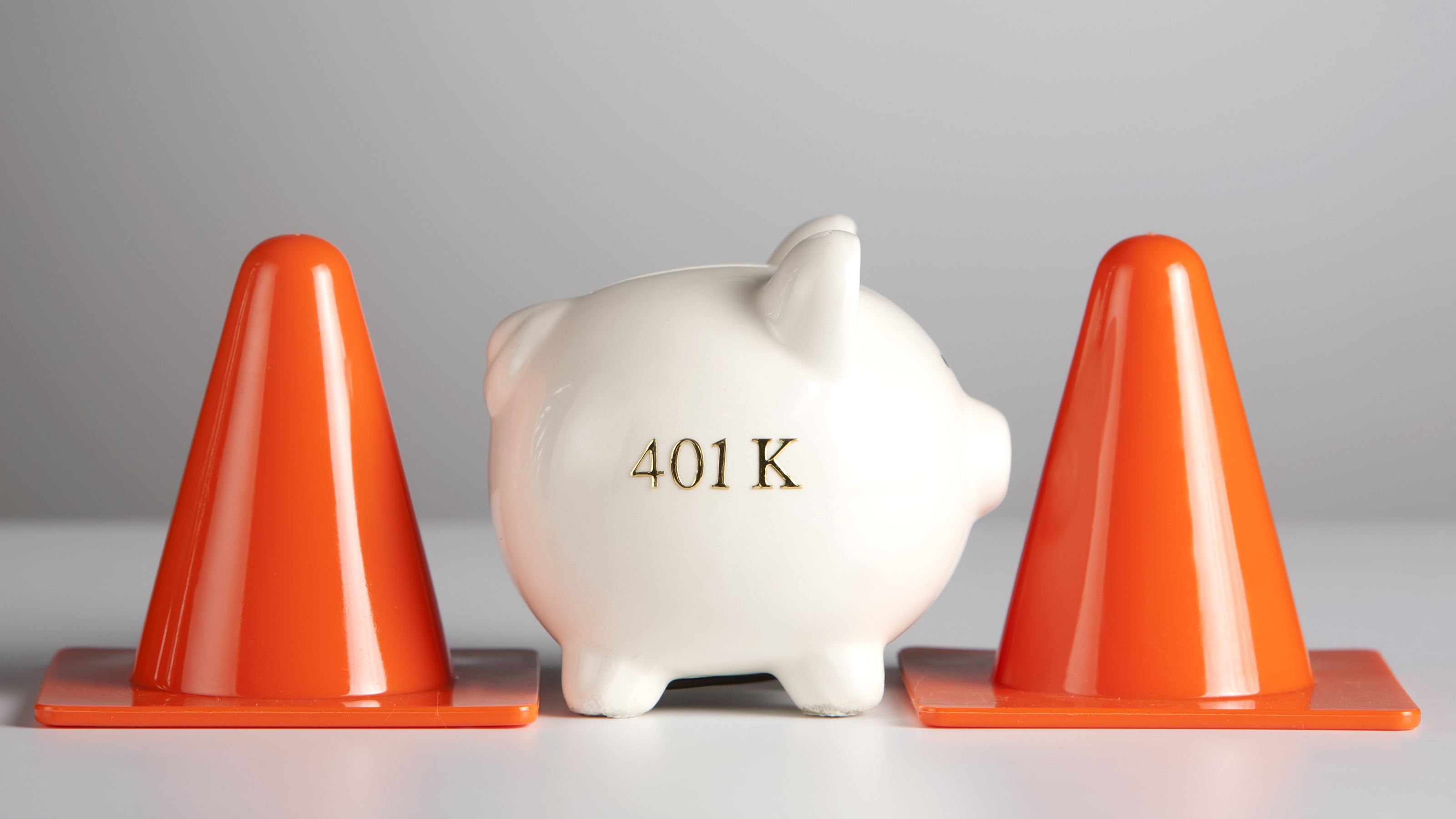 Caution cones sit on either side of a piggy bank.
