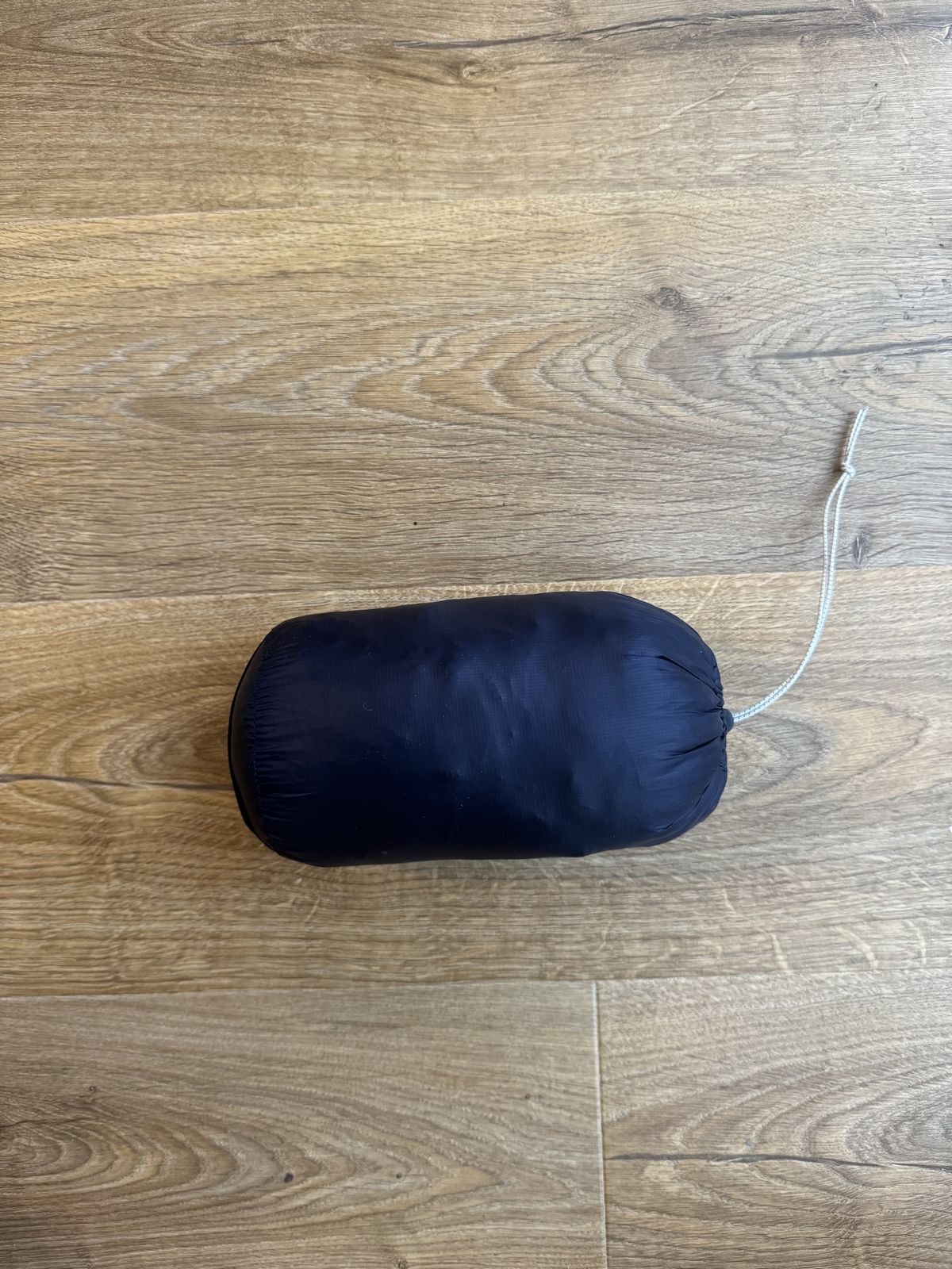 Navy blue jacket packed down in size to small cylinder.