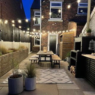 outdoor garden with bistro lights and wood dining table