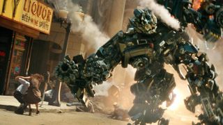 Still from the movie Transformers (2007). Here we see a Transformer robot with funs for arms in the middle of a battle in a street. In the background you can see people running away in terror.