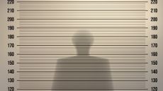 Police mugshot concept image showing silhouette of a man with back to wall.