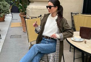 woman in white sweater, trench, and jeans