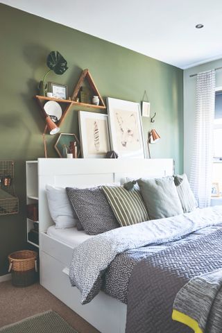 Spillett house: bedroom with green feature wall, white storage bed, blue-grey polka dot bedding, and triangular shelves