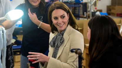 Catherine, Princess of Wales, wearing her Zara checked dress, spends time with members of the production team on the factory floor during a visit to Corgi, a family run textiles manufacturer