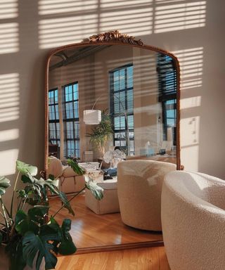 A living room being reflected by a large gold mirror