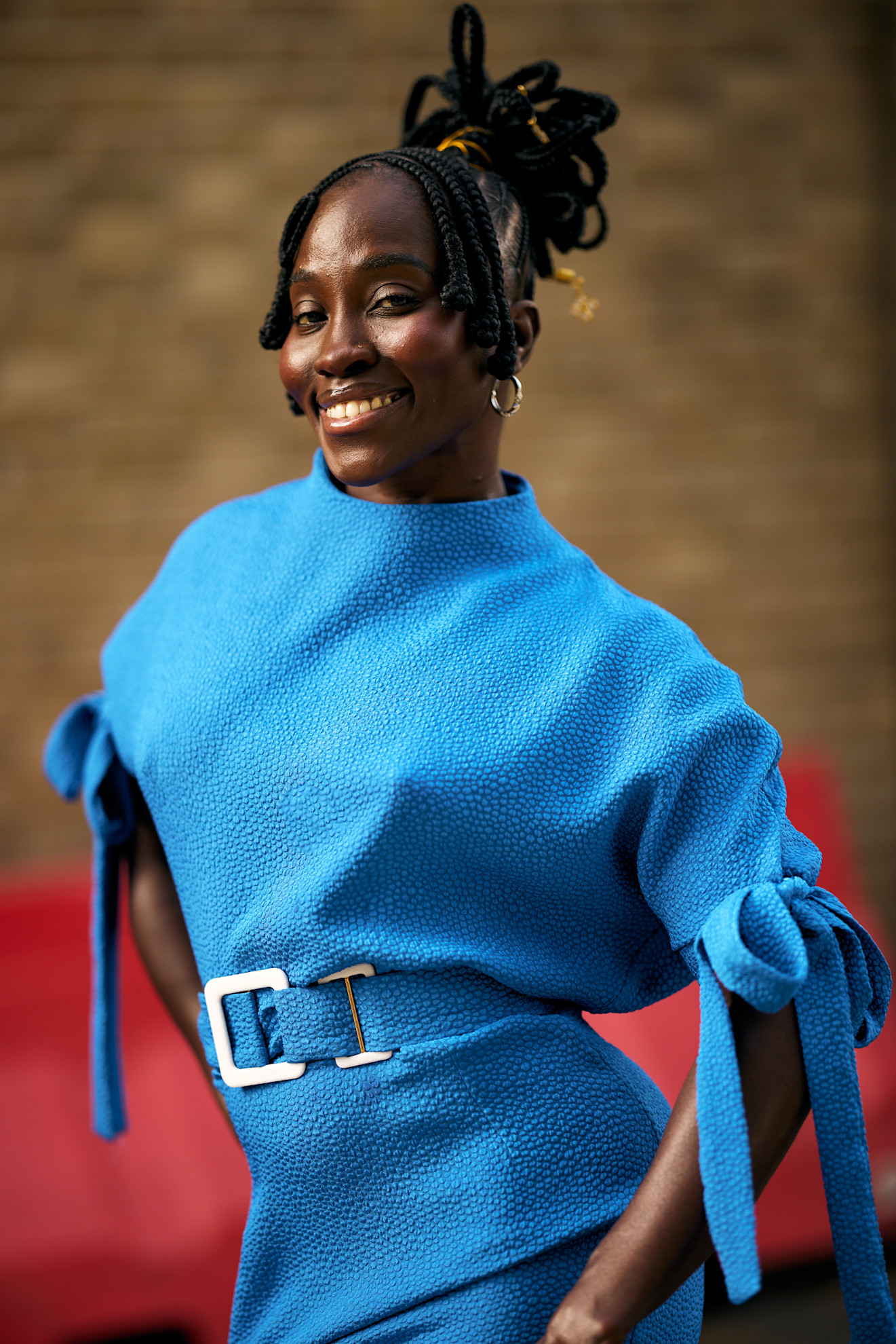 a black woman in a blue dress smiling with a braided updo
