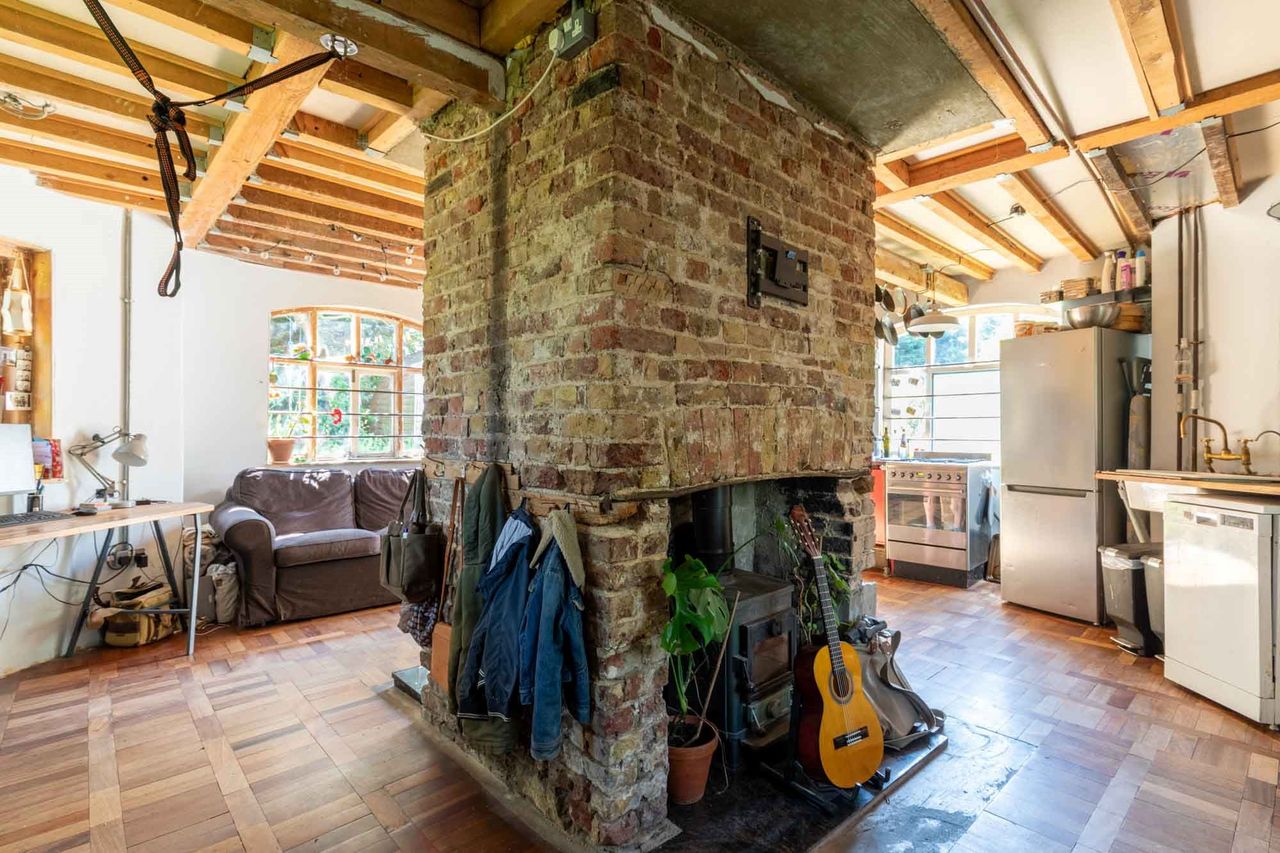 A fireplace built into a brick chimney in the middle of an open plan living room