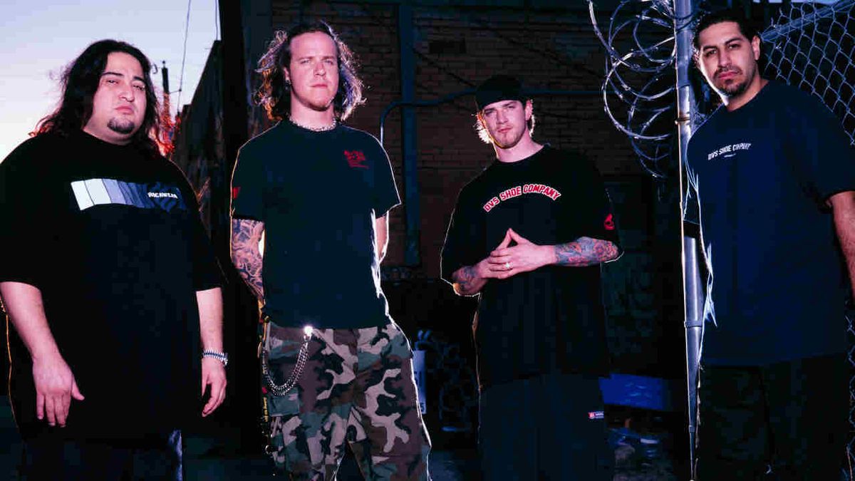 Fear Factory posing for a photograph next to a chain-link fence