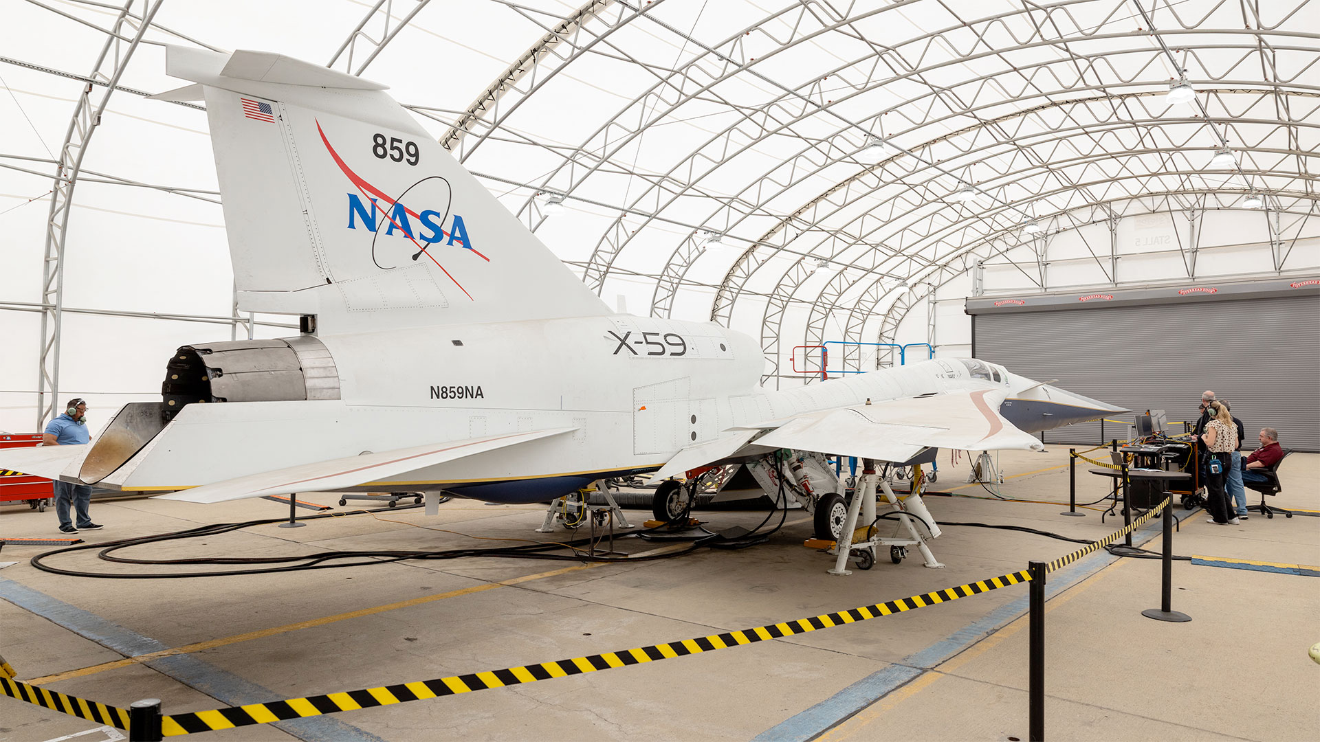 a large white jet with a NASA logo on its tail is parked inside a brightly lit hangar