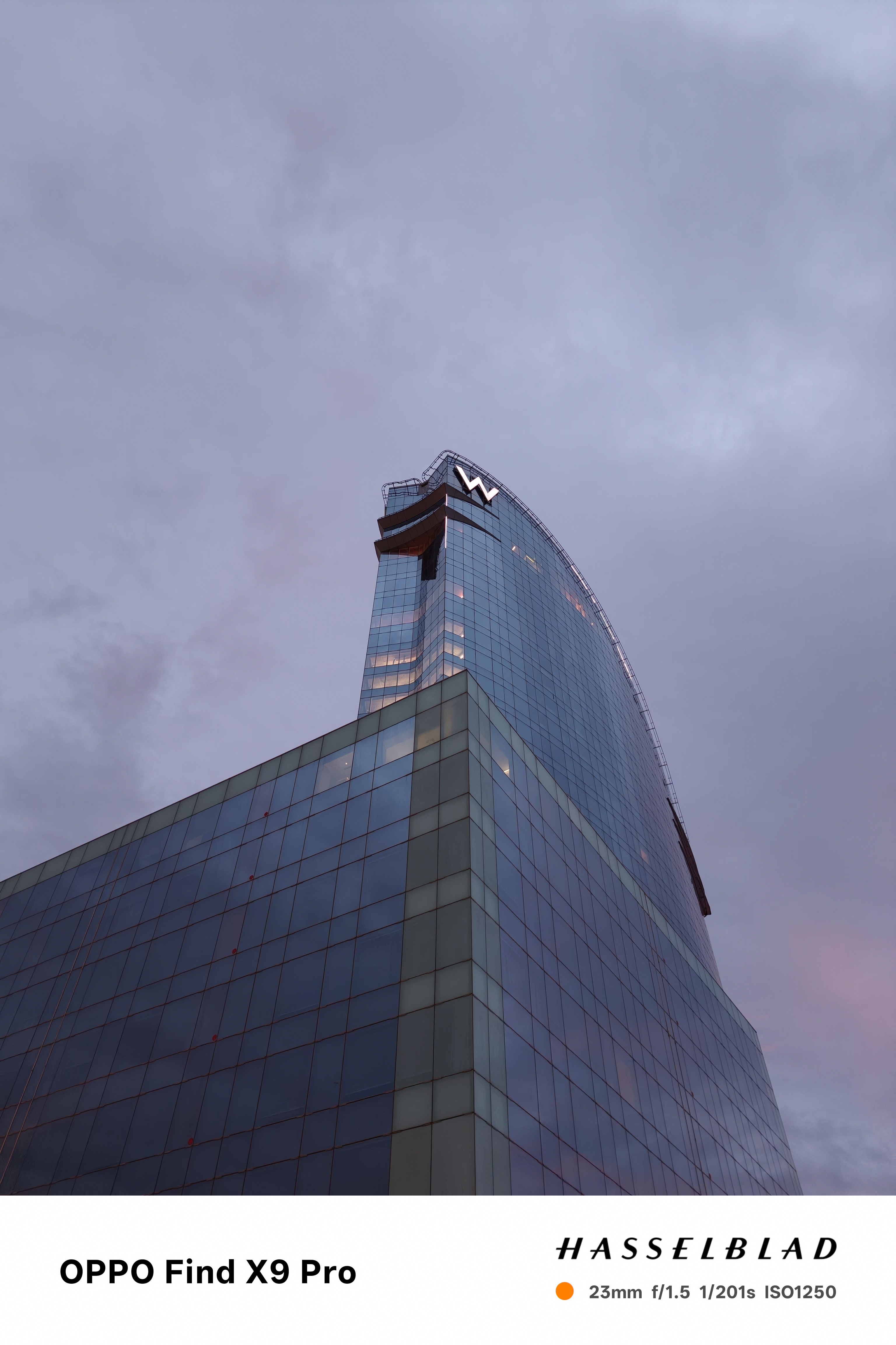 The W hotel seen from below in front of a cloudy sky with hints of red light from sunrise