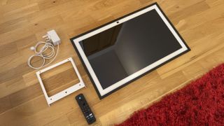 Amazon Echo Show 21 on floor with wall mount, power adaptor, and remote