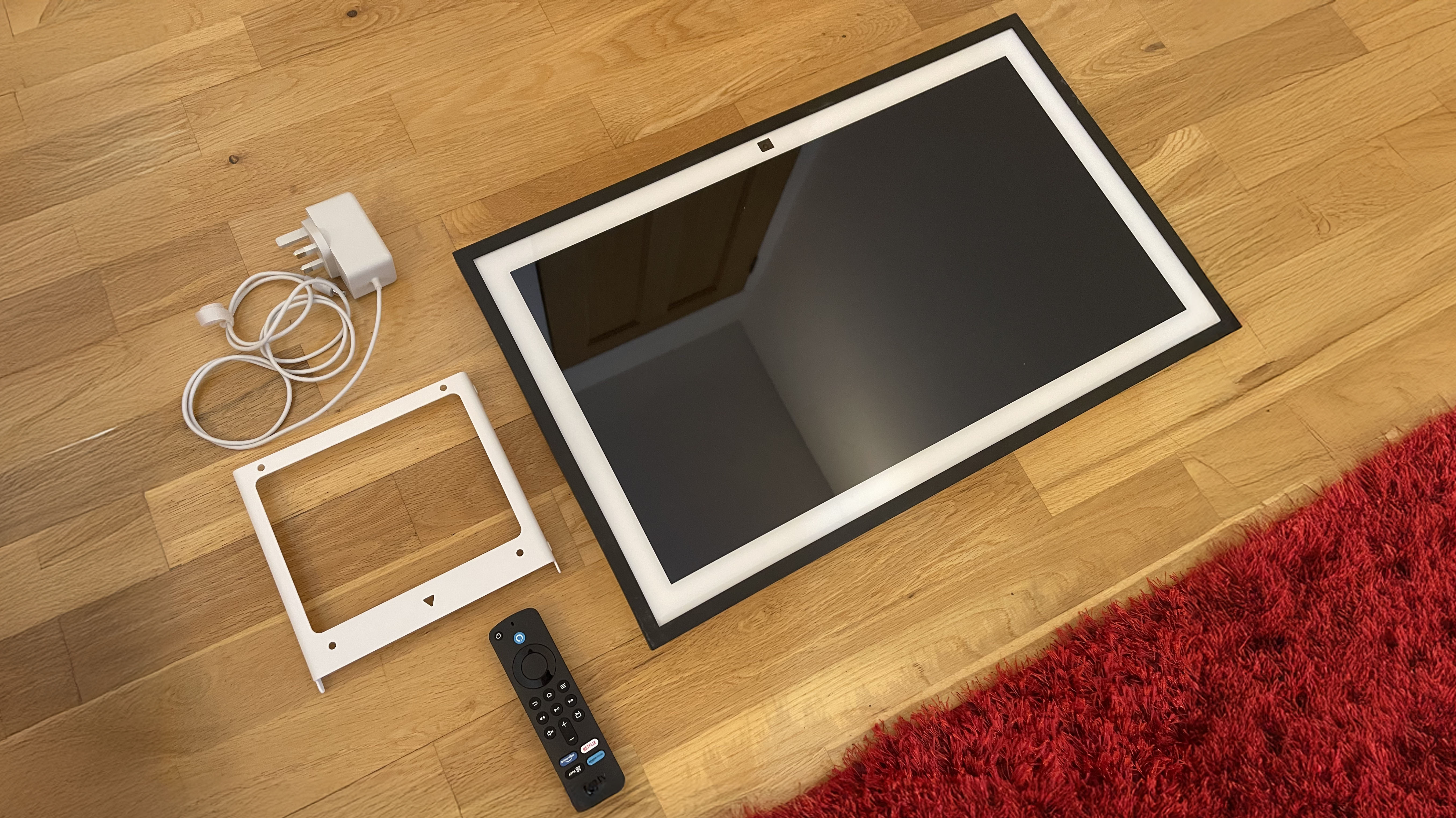 Amazon Echo Show 21 on floor with wall mount, power adaptor, and remote