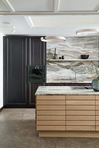 a kitchen with dramatic marble worktop and backsplash, and stone flooring