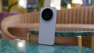 Vivo X500 Pro Max standing upright on a green marble table in a softly lit interior, with its large circular rear camera module facing the camera.