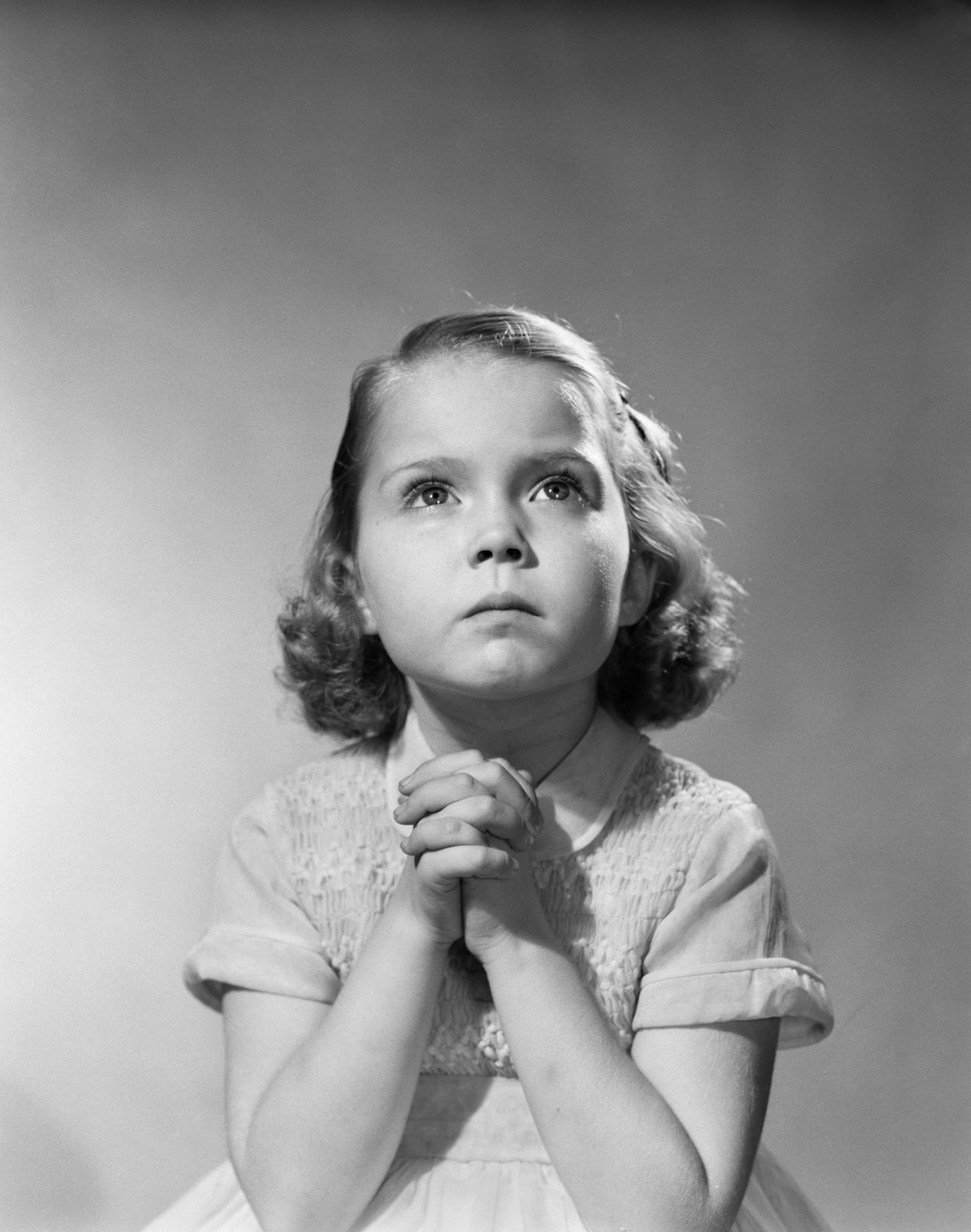 A young girl prays before bed.