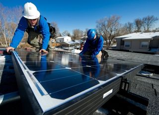 Contractors install solar panels on a residential roof.