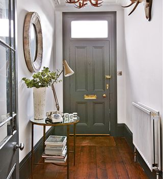 narrow hallway with grey door and round hallway mirror