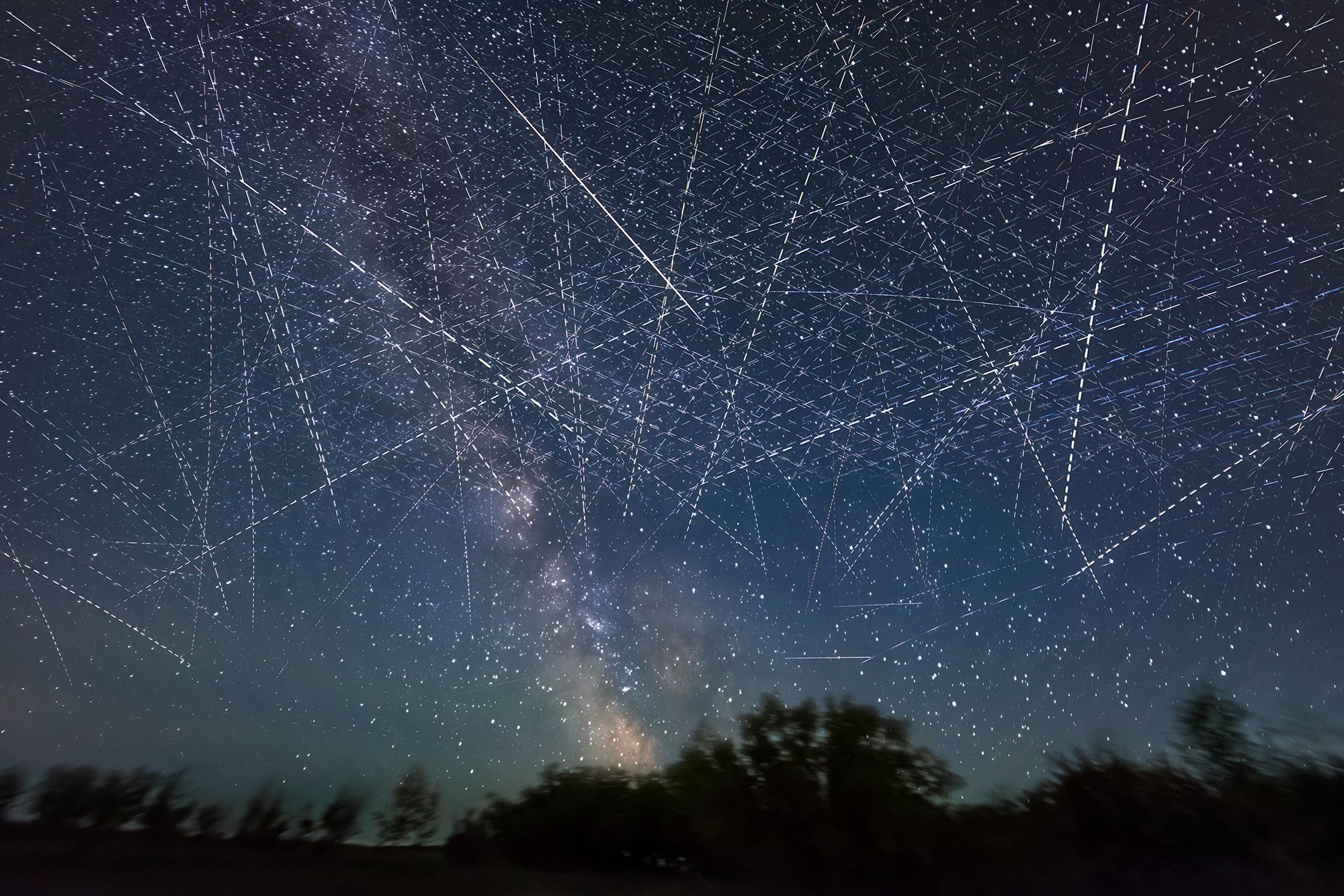 A series of white streaks of satellites in the night sky.