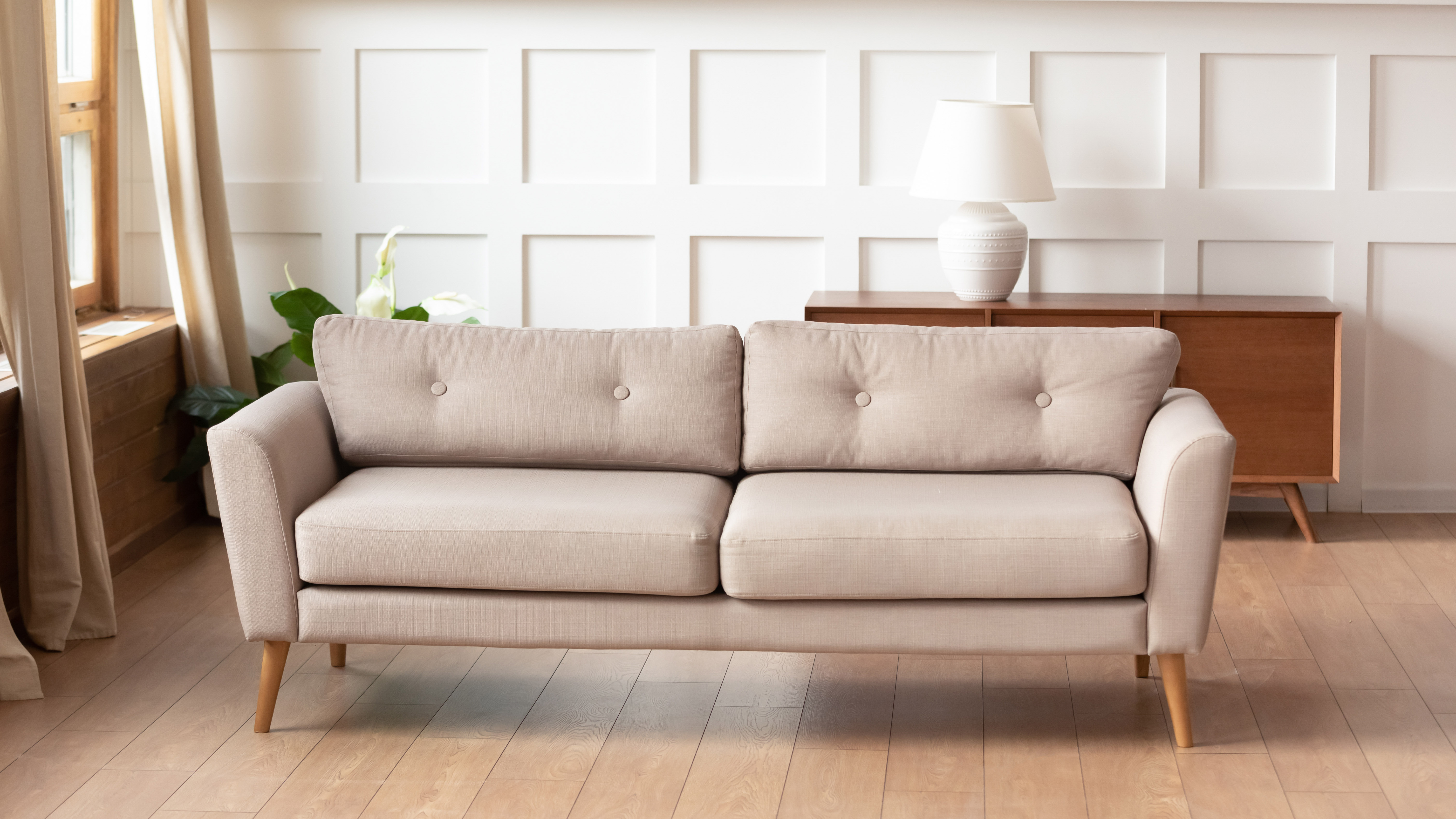 Beige two-seater sofa on wooden living room floor