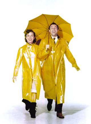 debbie reynolds and gene kelly in yellow rain jackets and with a yellow umbrella in a promo shot for Singing in the rain