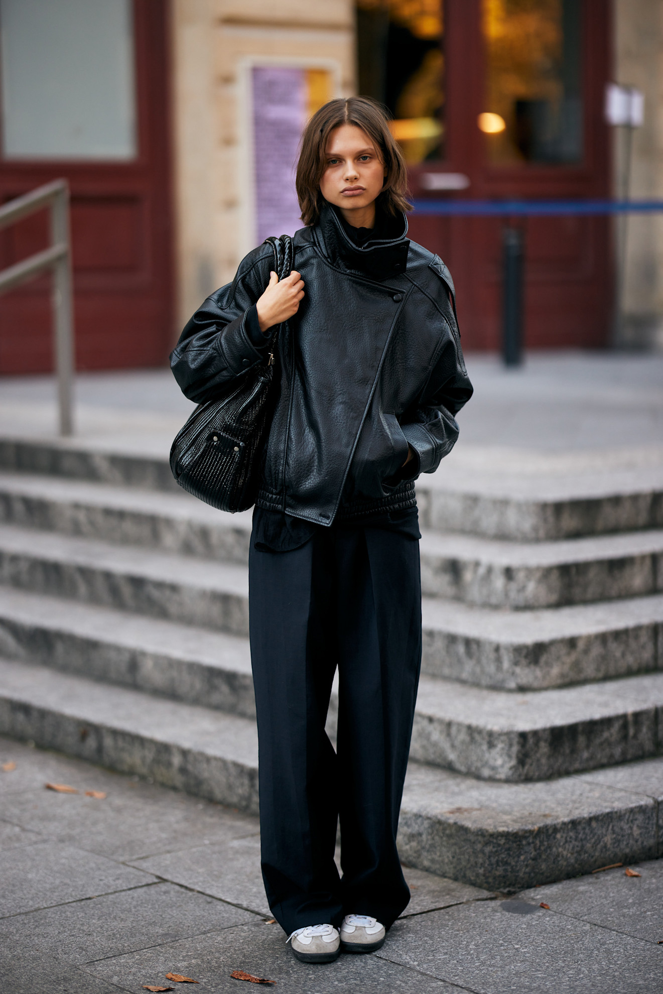 fashion week attendee wearing leather jacket, black pants, adidas sneakers
