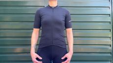 The black Madison Flux short sleeve cycling jersey in front of a green garage door 