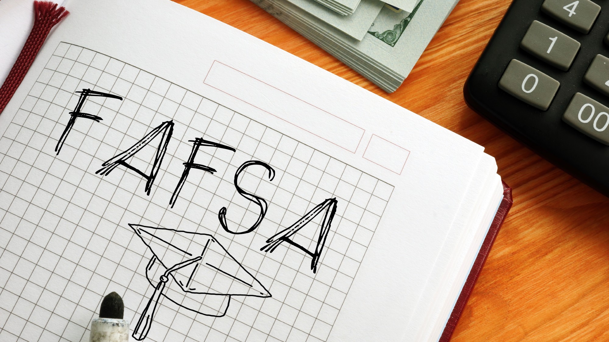 Notebook that says "FAFSA" with sketch of graduation cap underneath it