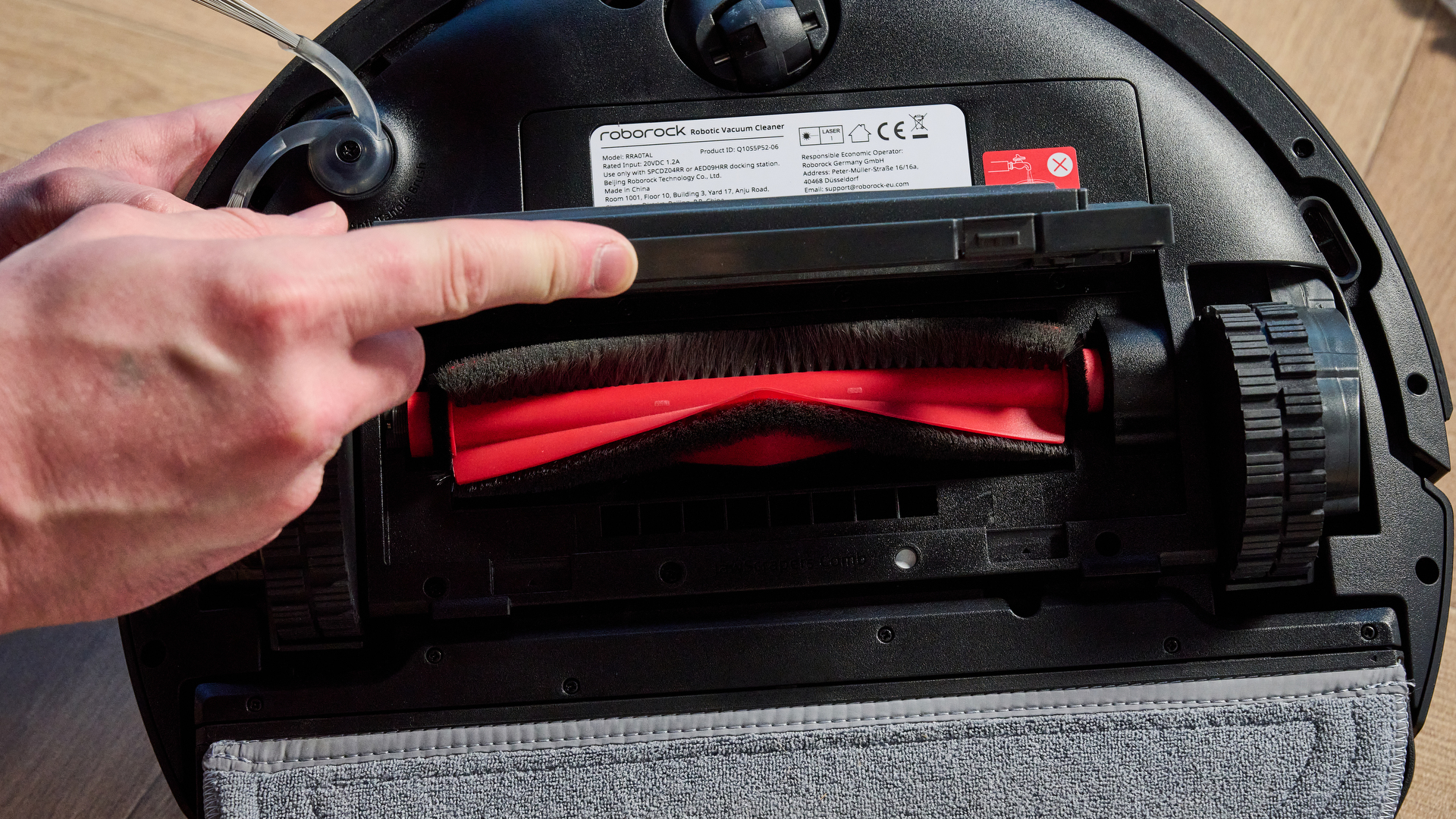 Roborock Q10 S5+ photographed on a wooden floor in front of a blue background