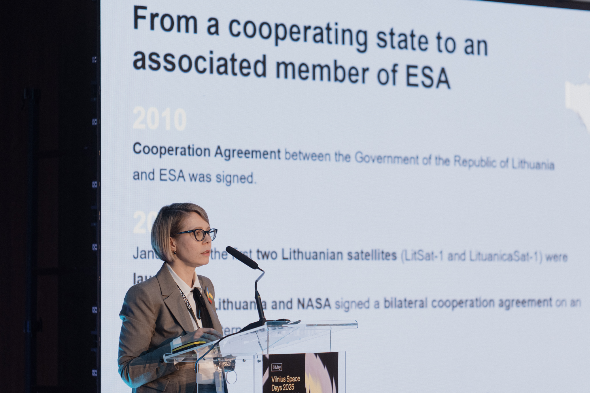 A woman stands at a podium giving a presentation.
