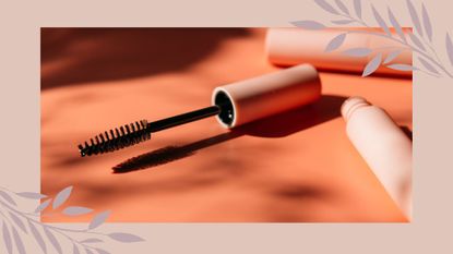 A mascara tube and wand on an orange background to illustrate how often should you replace your mascara