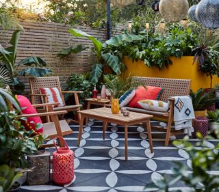 modern patio with patterned paving, tropical plants and yellow painted wall