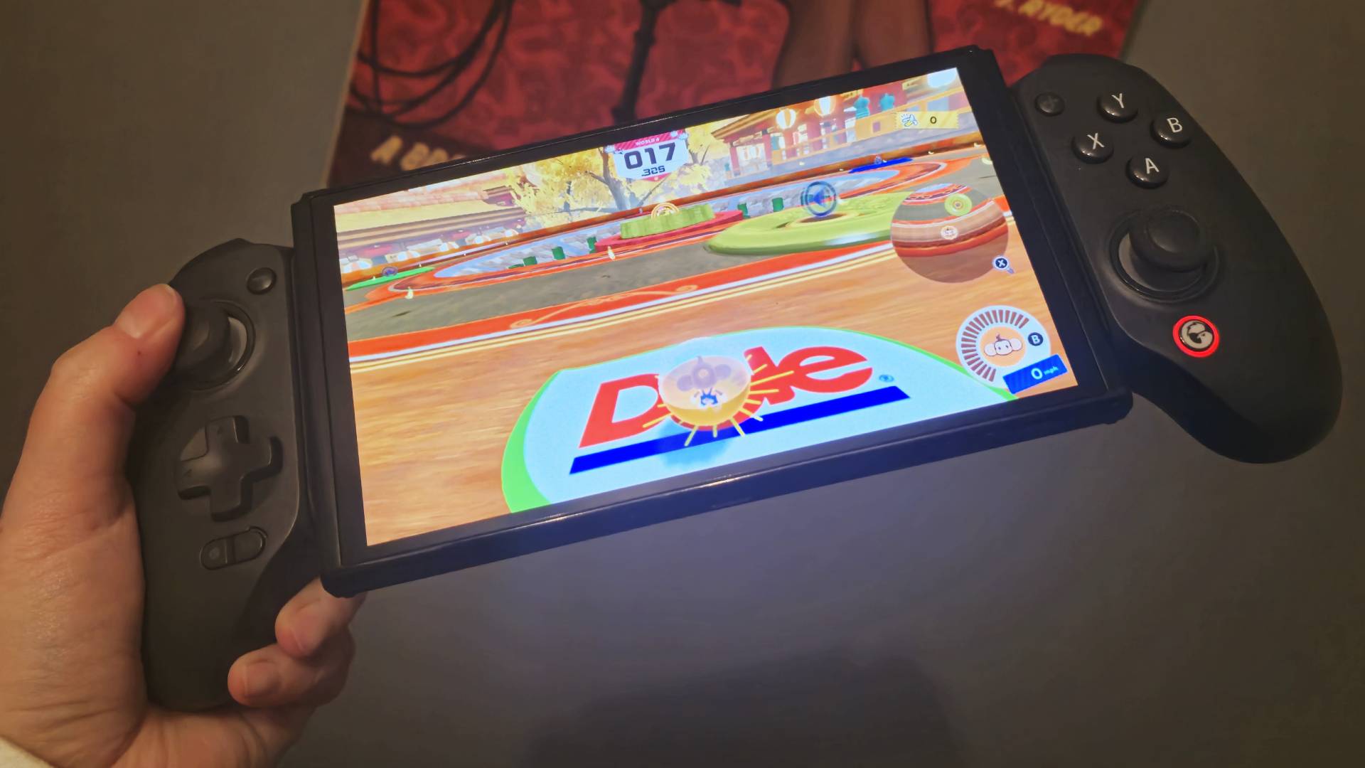 Foto de la autora Rosalie Newcombe sosteniendo un GameSir G8 Galileo+ con fondo gris y Super Monkey Ball en la pantalla de Switch.