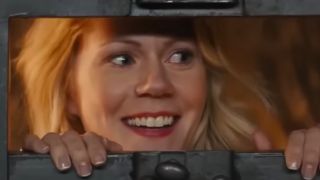 A smiling blonde woman looking through a slot in a door in Kingsman: The Secret Service