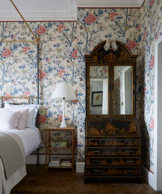 bedroom with floral wallpaper, dark wooden floor and furniture, metal four poster bed