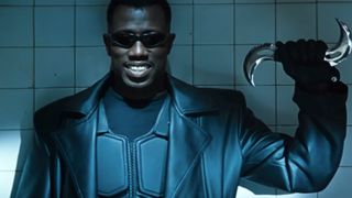 Wesley Snipes as Blade, smiling in all black and sunglasses with a silver weapon in his left hand. 
