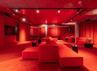 Red lighting in a lounge area with square sofas