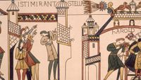 Photo of the portion of the Bayeux Tapestry depicting people pointing up at a flaming comet.