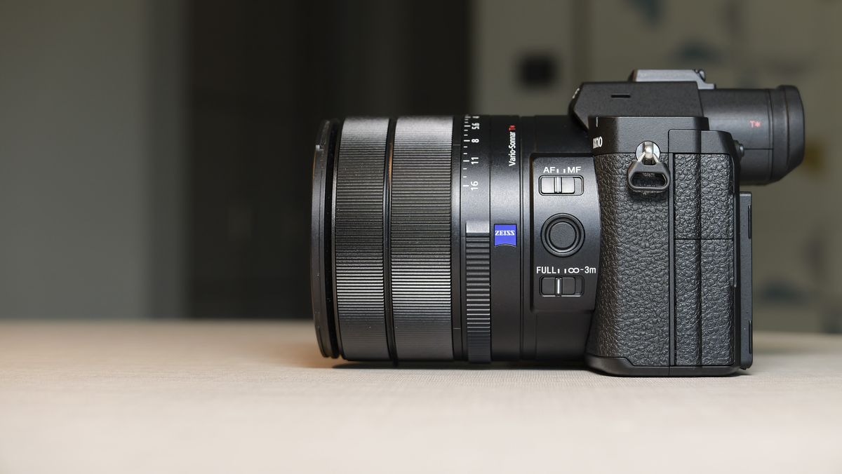 The side profile of the Sony RX10 V bridge camera, on a white table with a patterned wallpaper background, its lens is retracted