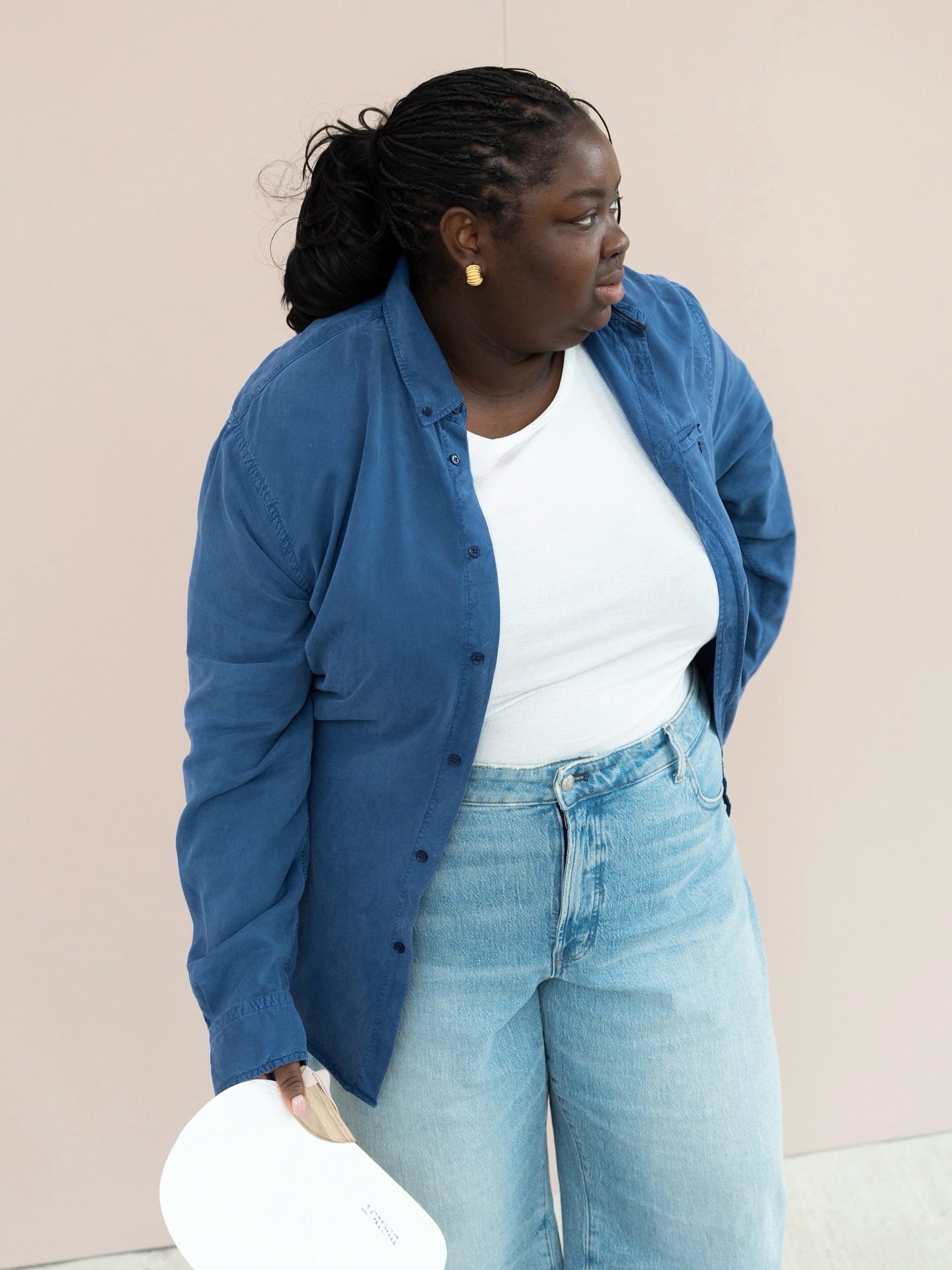 An image of @abimarvel wearing a white t-shirt with a button-down and blue jeans, an example of the best transitional basics.