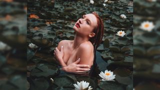 Kelsey Johnson self-portrait in a lake surrounded by lilys and lotus flowers