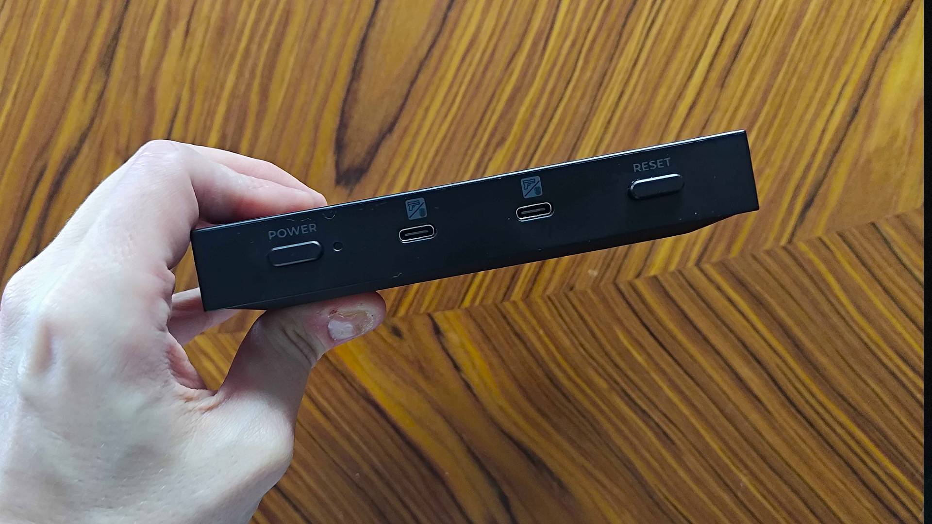 Hand holding G'AIM'E Time Crisis console with front ports facing camera.